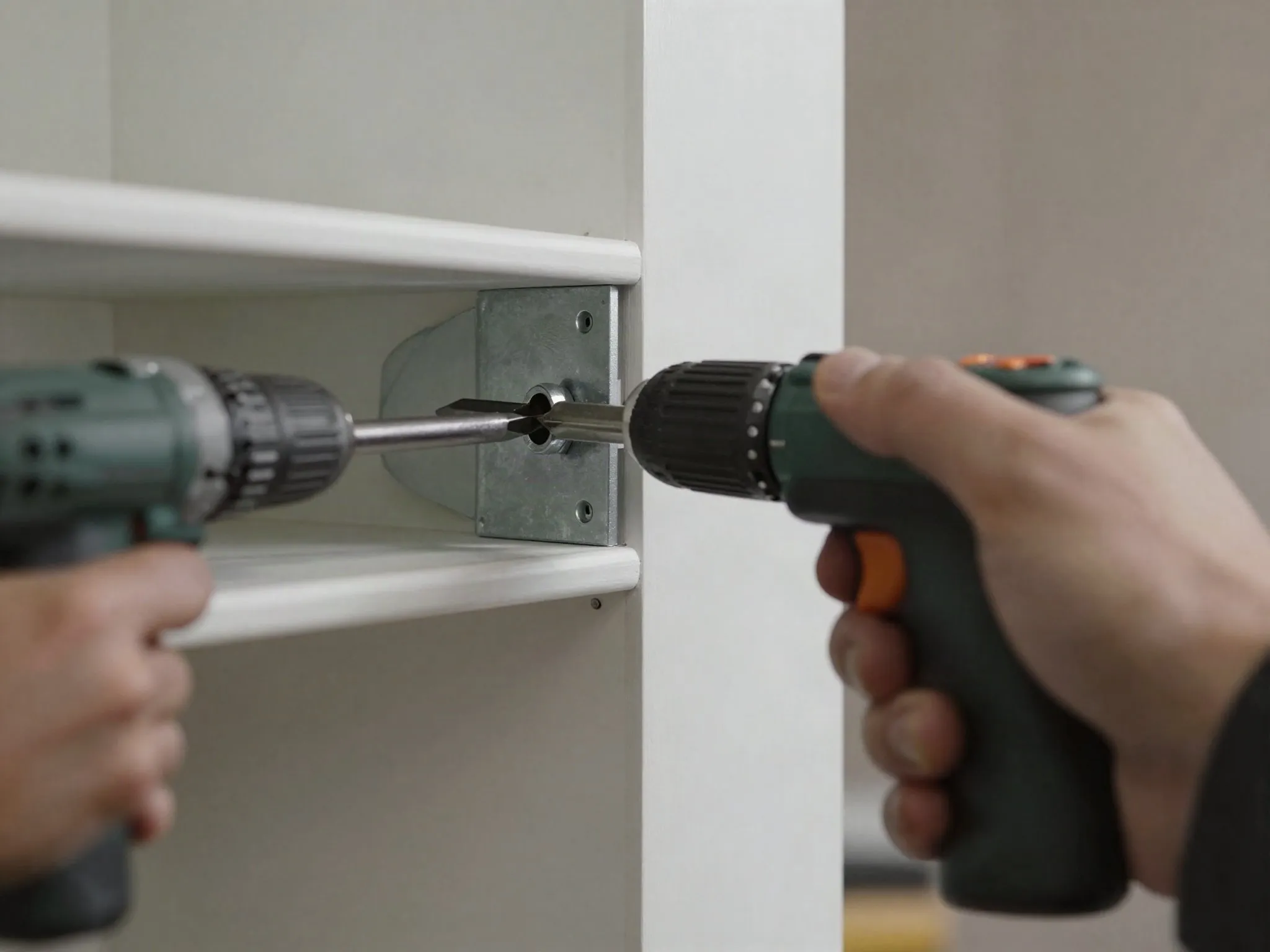 A hand using a drill to install a hidden metal shelf bracket into a wall stud