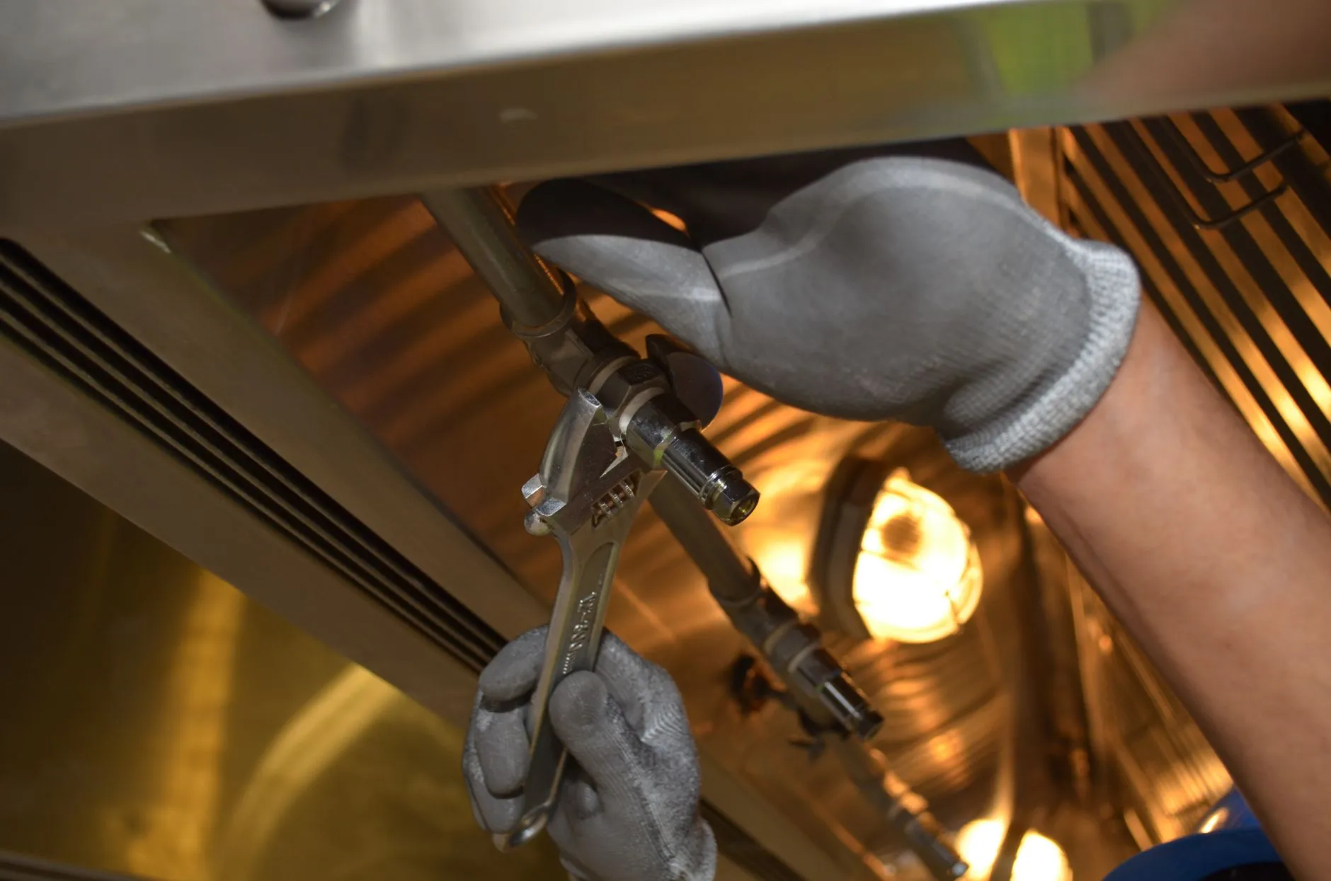 Technician's hand adjusting a thermostat on a wall near a furnace vent