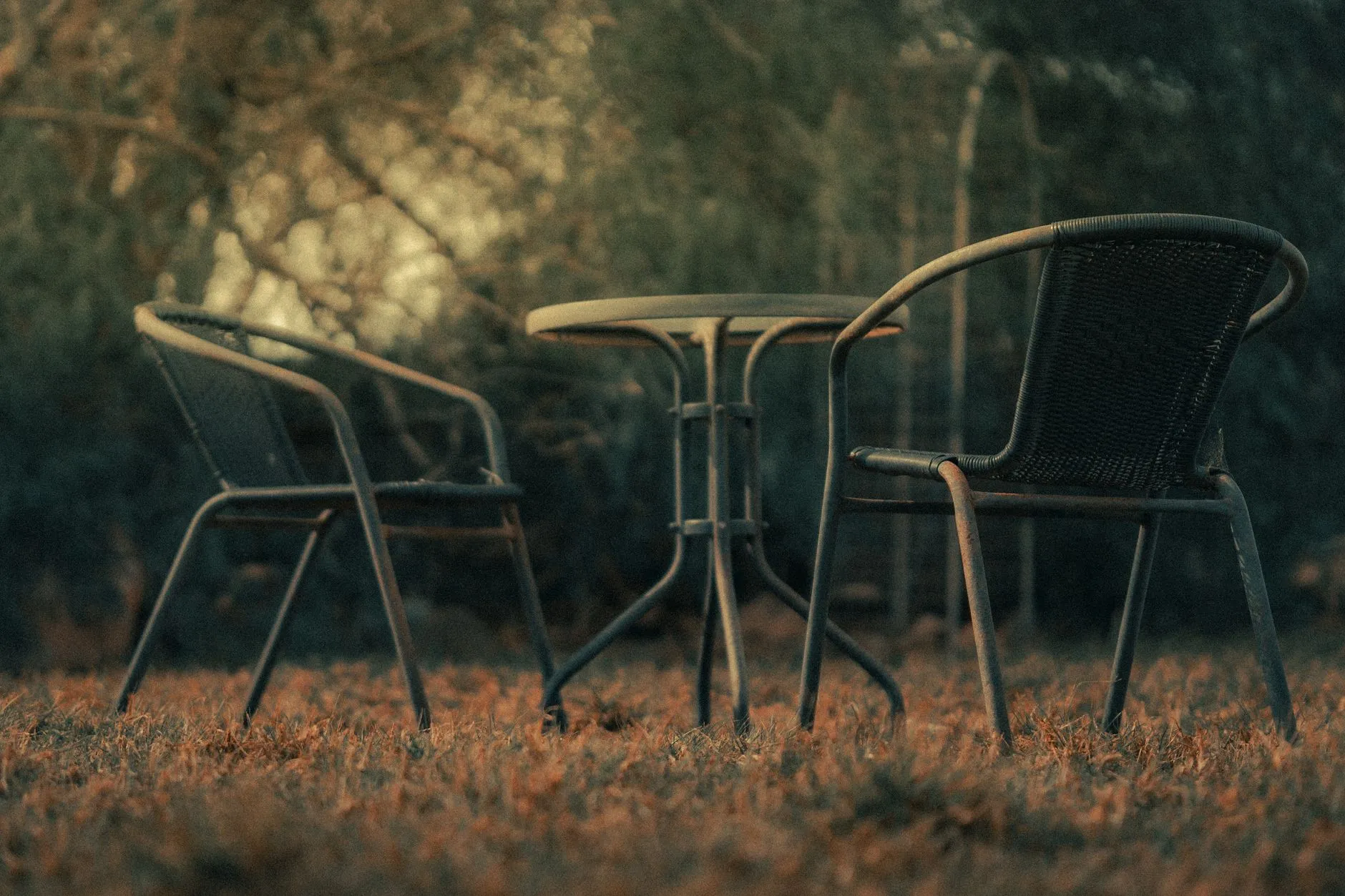 An uncovered metal bistro table and chairs left out as the growing season ends
