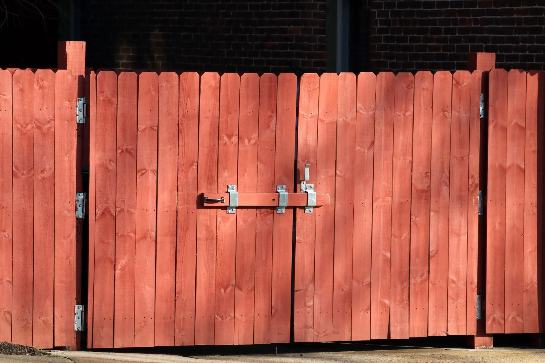 A wood fence gate with hinges and a latch